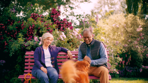 Man and woman sitting together on a bench with a dog.